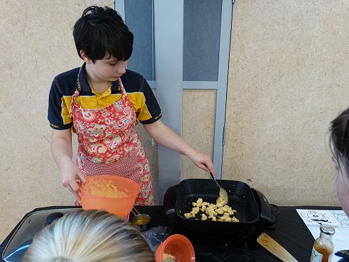 Hayley adds the sauce and meat to the cooking pan