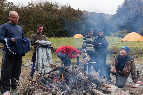 Barry Timmings, Josh Stoddard, Ben Wishart (crouching), Boen Deng, Lachlan Kenneally, and Jin Kim enjoy the fire after a day in the snow.  