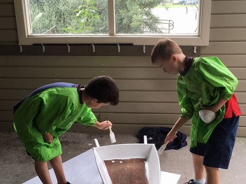 Balin and Toby carefully painting an old wooden wheelbarrow to plant lavendar in.