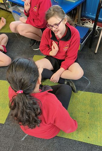 Emily teaching a partner the sign for need