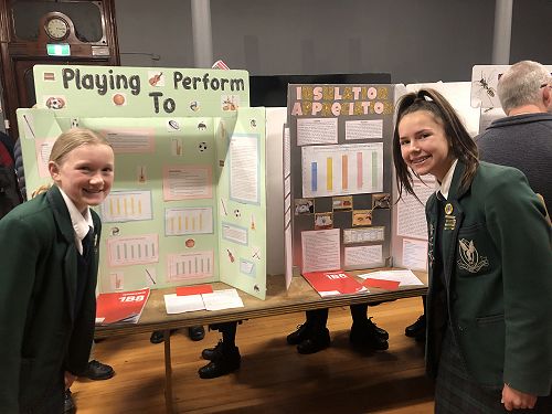 Alice Porter and Alexandra Pratley stand with their boards about exam performance and insulation