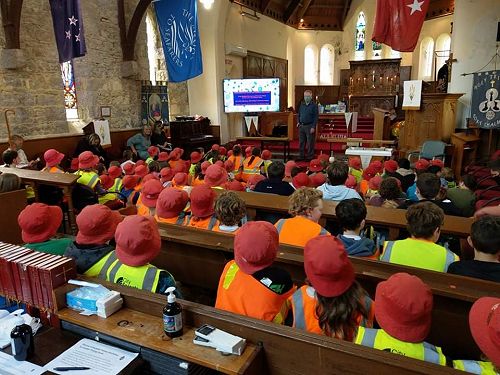 Hi vis and hats as children meet inside the church.