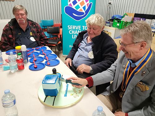 President Eric Nolan and Rodger Little watch DG Martti cut the 50th celebration train cake