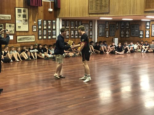 Head of Sutherland, Sam Potter, congratulates Head of Bennett, Liam Anderson, on winning the Matthew Allen Cup Singing competition and hands over the Lake Shield.