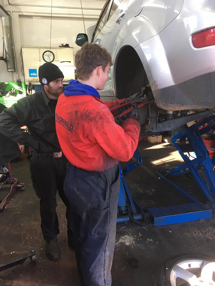 Archie Calder replaces brake pads at Automotive Solutions under the watchful eye of his mentor