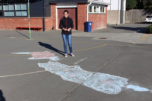 Emma and her chalk drawn New Zealand.