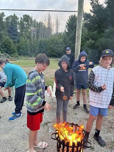 Harrison attempting his new s'more making technique. Tom's marshmallow is IN the fire and Alex is inspecting his.