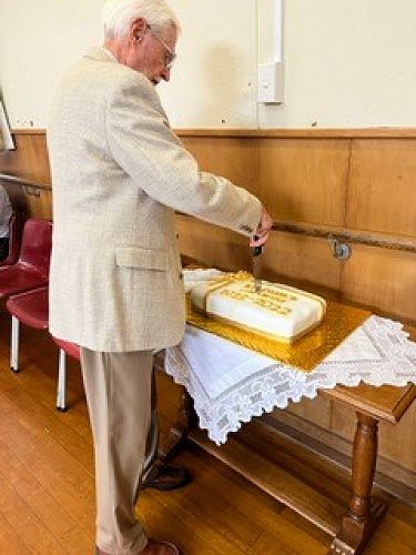 Parishioner Geoff Ryan cuts the celebration cake.