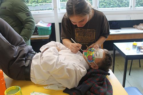 Students paint masks on each other