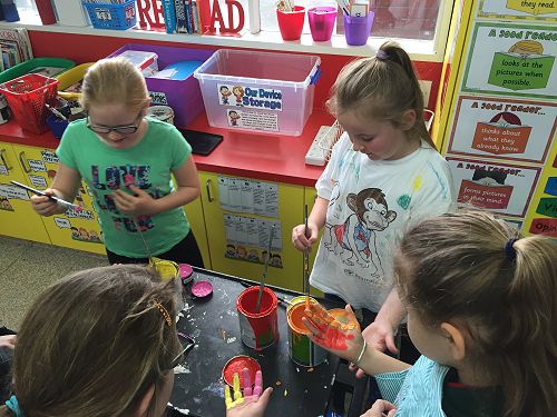 Annabel and Caitlyn help the Year 3 students with the mural