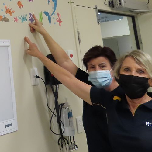 Lower Blue Mountains Rotarians Carolyn Fitzpatrick and Michele Ellery (left) admire colourful decorations added to the walls of the family room at Nepean Hospital’s Emergency Department.