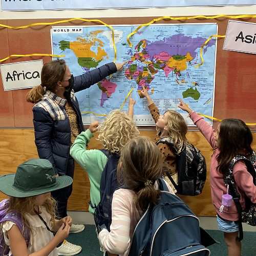 Teacher discussing world map with their class.