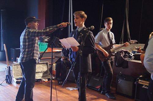 Robert Scott adjusts Jordan Frost's microphone as he sings "North by North".