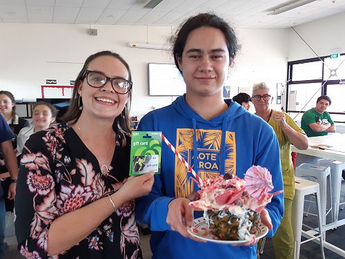 Cindy awarding a prize to Rahui in the dessert making competition