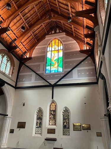 New window detail: tree roots in the water through the Southland land, mountains and sun depicting growth.   