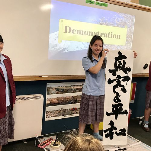 Our Fuji Girls demonstrating  Japanese calligraphy. The banner the girls made is the Roncalli motto to seek Truth and Peace.