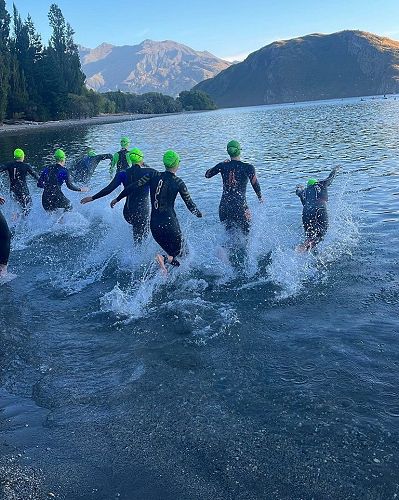 Swimmers race into the water to start their leg