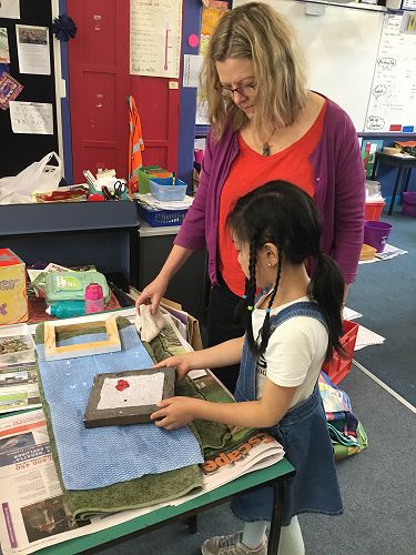 Janine making paper, and decorating it with flowers.