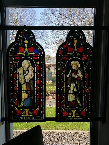 Salvaged stained glass windows reused - with glimpses through to the birdsong filled graveyard beyond.