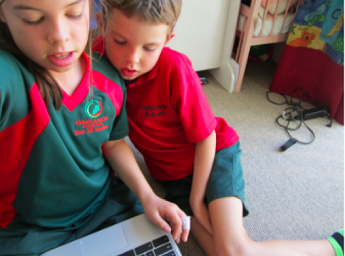 Hannah teaching her brother to use Google Slides. 