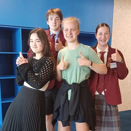 JPII Alumni joining the student in a "Men in Black" pose