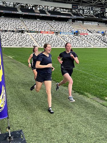 Rhiarna powering over the finish line with teammates Poppy and Anya in support