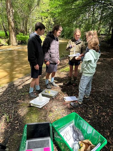 Jacob Begg and Declan Dudin offering guidance to the Year 6 Limehills students on how to measure turbidity of the stream sample.