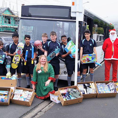 L-R Year 9 Nick Reid, Year 10 students Ahnaf Monirul and Mrigank Das, Year 9 Finn Boucher and Year 10 students Louis McNabb, Ali Al Tooq and Adam Salisbury pictured here with Stock the Bus staff
