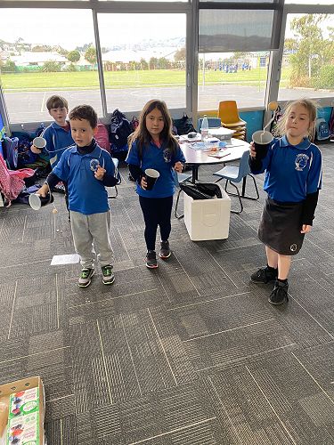 Nico, Xavier, Lyric and Kaylee are playing catching the ball in a cup.