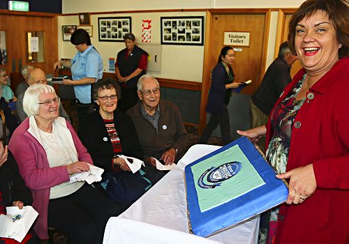 Julia Russell, Director Enliven showing some village residents the delicious Trusted Brands celebration cake