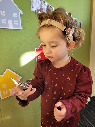 Ellie May Adams playing a language game with photos of her friends at Dunedin Playgroup