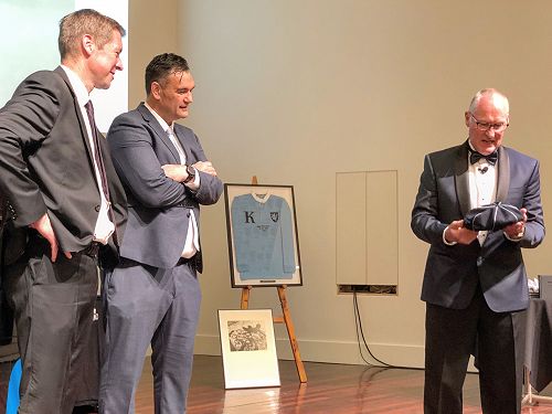 Rector Dan Reddiex and Glen Denham await the presentation of the first King’s High’s commemorative cap by MC, Steve Davie