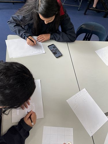 Using Google Images for Ideas.  Also shown is another year 9 student using her cellphone to trace an idea.