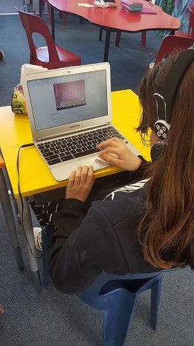 Emma using an online tutorial to code a rock band on scratch.
