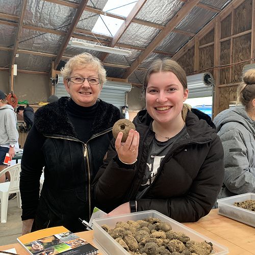 Mrs Bishop (Director of Agribusiness at Columba College) and Jessica Sime appreciate this dung work of art!