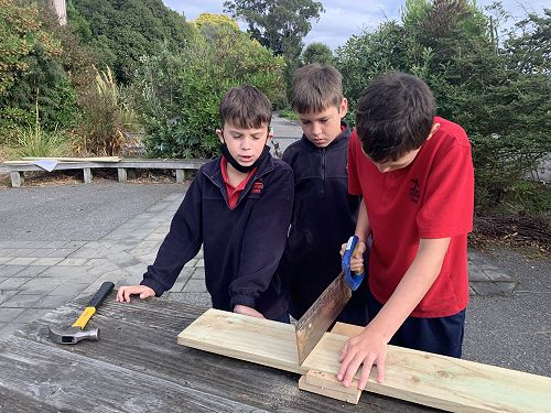 Noah cutting a piece under the supervision of group members Riwai and Xion. 