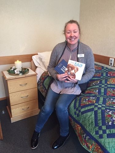 Enliven Pastoral Care Visitor Donagh Booth holding up some children's picture books on grief which are included in the End of Life comfort baskets.