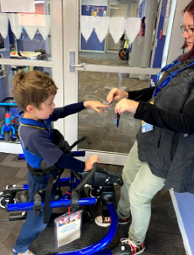 Rylee is saying he wants "more" time in this trial walking frame to his teacher Liz Jane.
