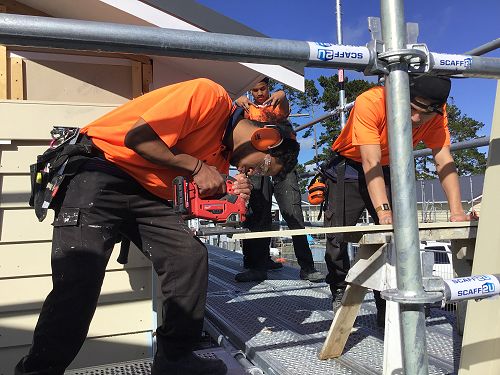 Markus works on a house's weatherboard