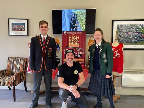 Thomas Hill, Doug Kamo and Grace Johnston in front of the High School Musical display in the College office