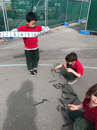 Ethan supporting Dominic writing numbers.