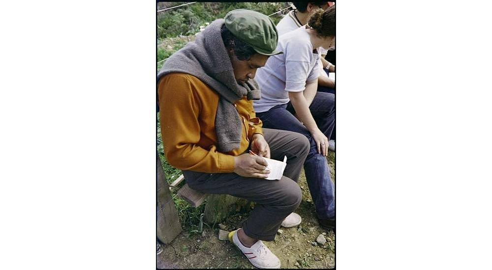Hone Tuwhare writing in his notebook during a stop on the 1975 Maori Land March between Otiria and Hikurangi; circa 17-18 September 1975.