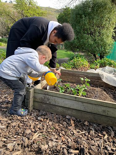 Noah and Asinate watering the garden at Sumner