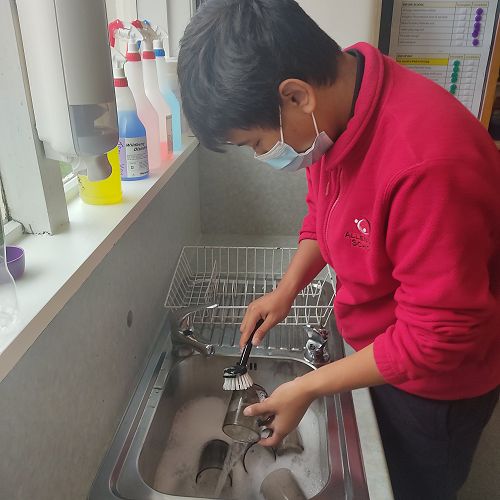 Hugo demonstrates kindness when he helps to wash the dishes.