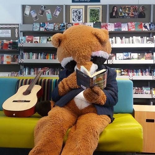 School Mascot, Riccy the Racoon, checking out one of the books from RHS Book Club.