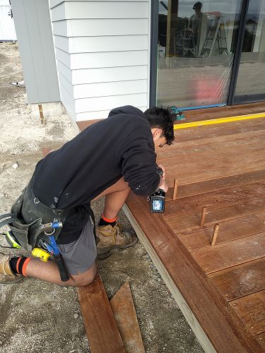 Chase drilling holes for screws on a deck. Chase has worked on this house right from the start. Just a few more finishing touches.