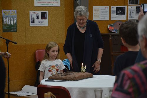 Oldest member (Jenny Pattrick, daughter of Tim and Don Priestley) and the youngest member (Scarlett Powell) prepare to cut the anniversary cake.