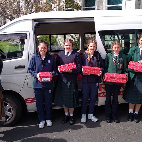 Year 9 Students present gift boxes to the masked and fully-vaccinated staff from Presbyterian Support Otago, Mrs Jasmin Enright and Ms Emily Lane