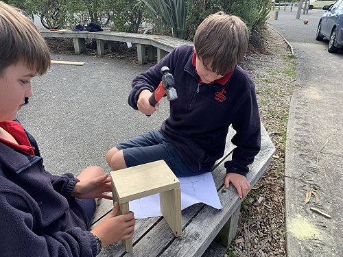 Ben holding part of the bug hotel while Jake hammers in the nail. 